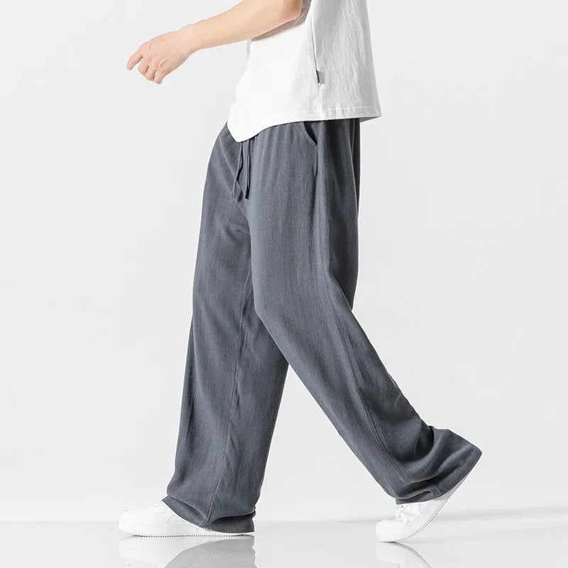 Man wearing beige bamboo fibre drawstring waist trousers with a cropped, straight leg.