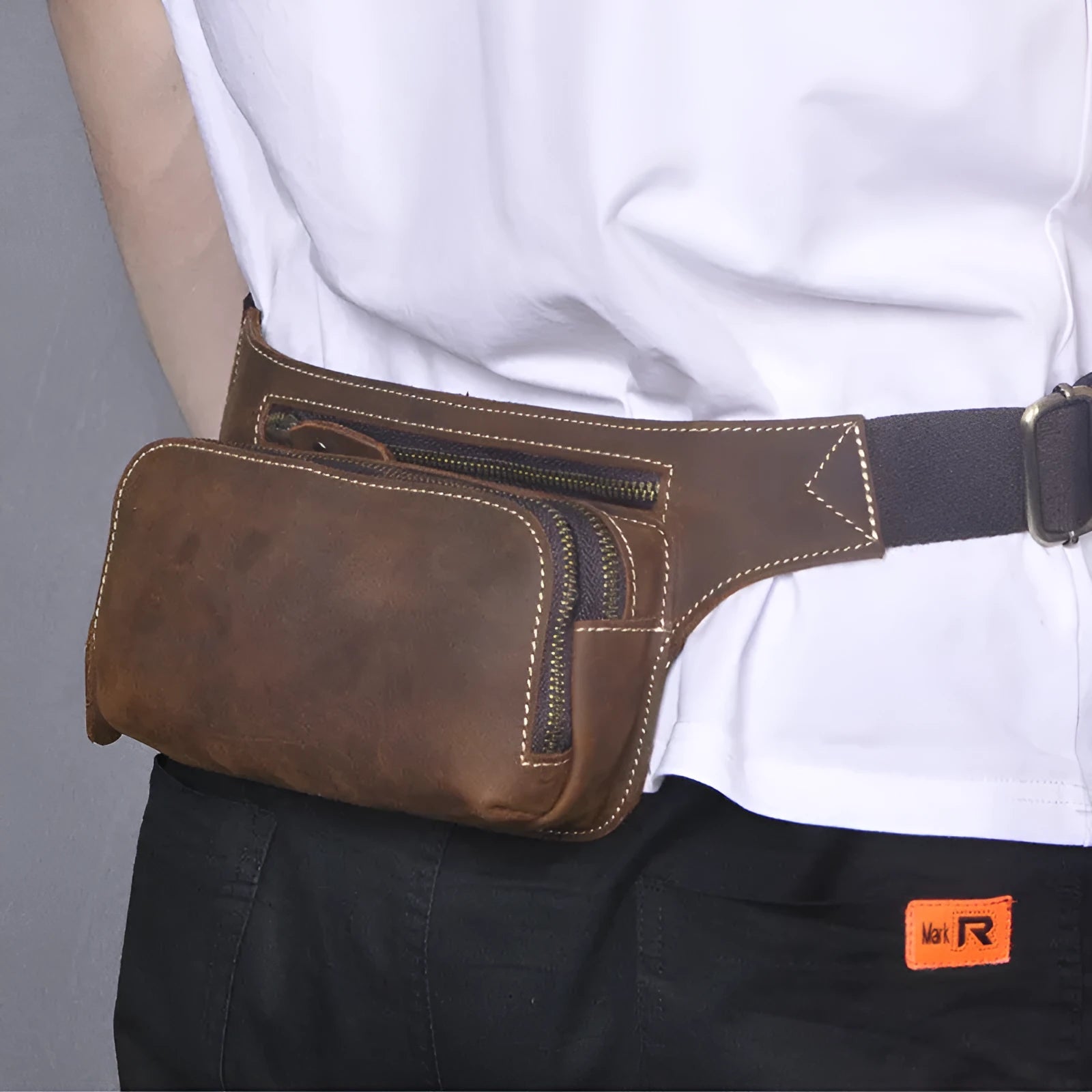 Brown top layer cowhide men's waist bag with pull-cord closure, shown open to reveal internal laptop sleeve and phone pocket.