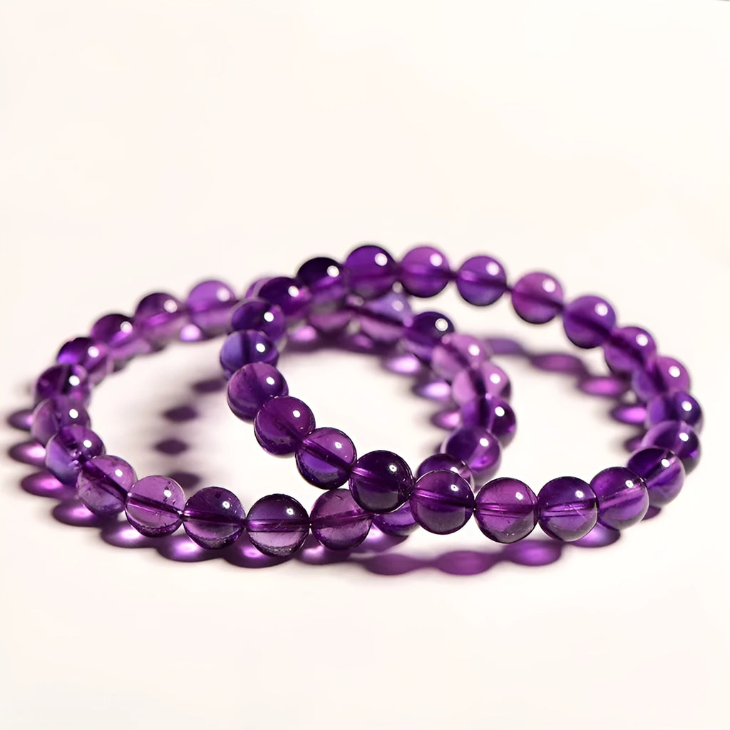 Natural violet amethyst crystal bead bracelet with polished, scattered beads on a neutral background.
