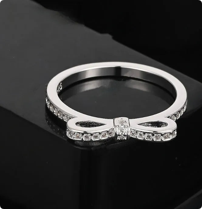 Silver electroplated sterling silver ring with a wide bow design set with clear zircon crystals.