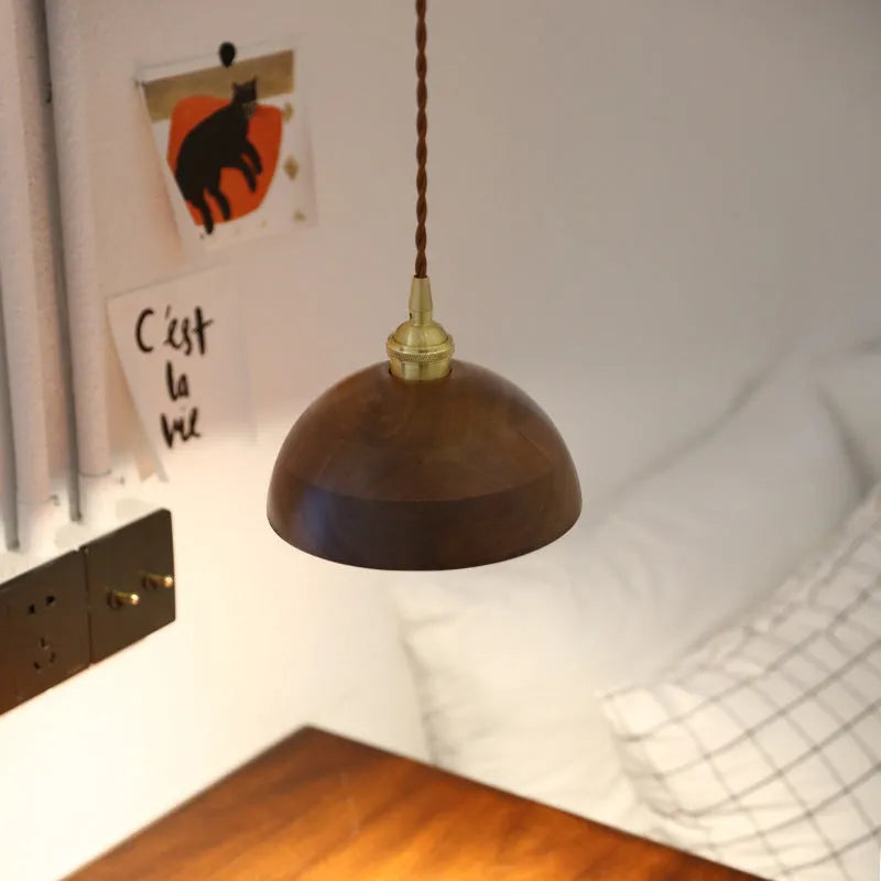 Black walnut and copper single-head droplight chandelier suspended from a ceiling.