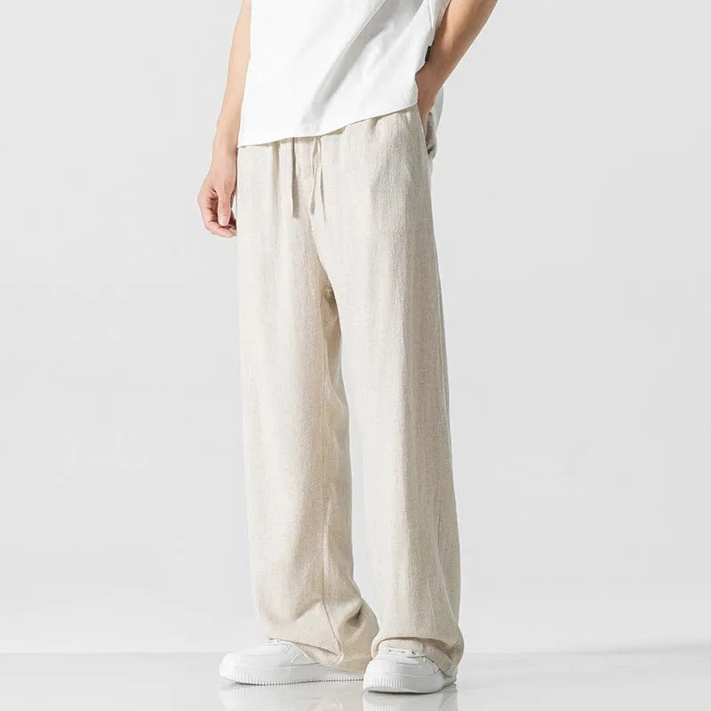 Man wearing beige bamboo fibre drawstring waist trousers with a cropped, straight leg.