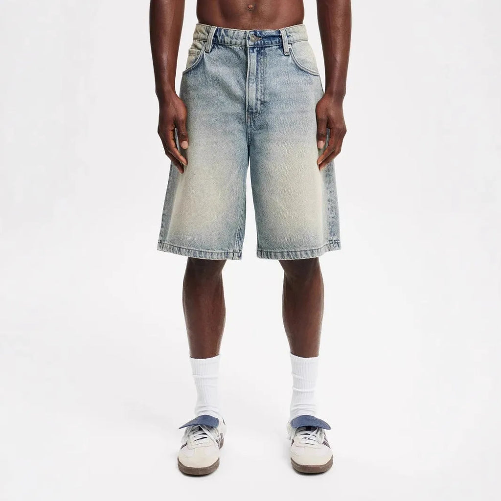 Men's loose fit light blue straight leg denim jeans on a grey background