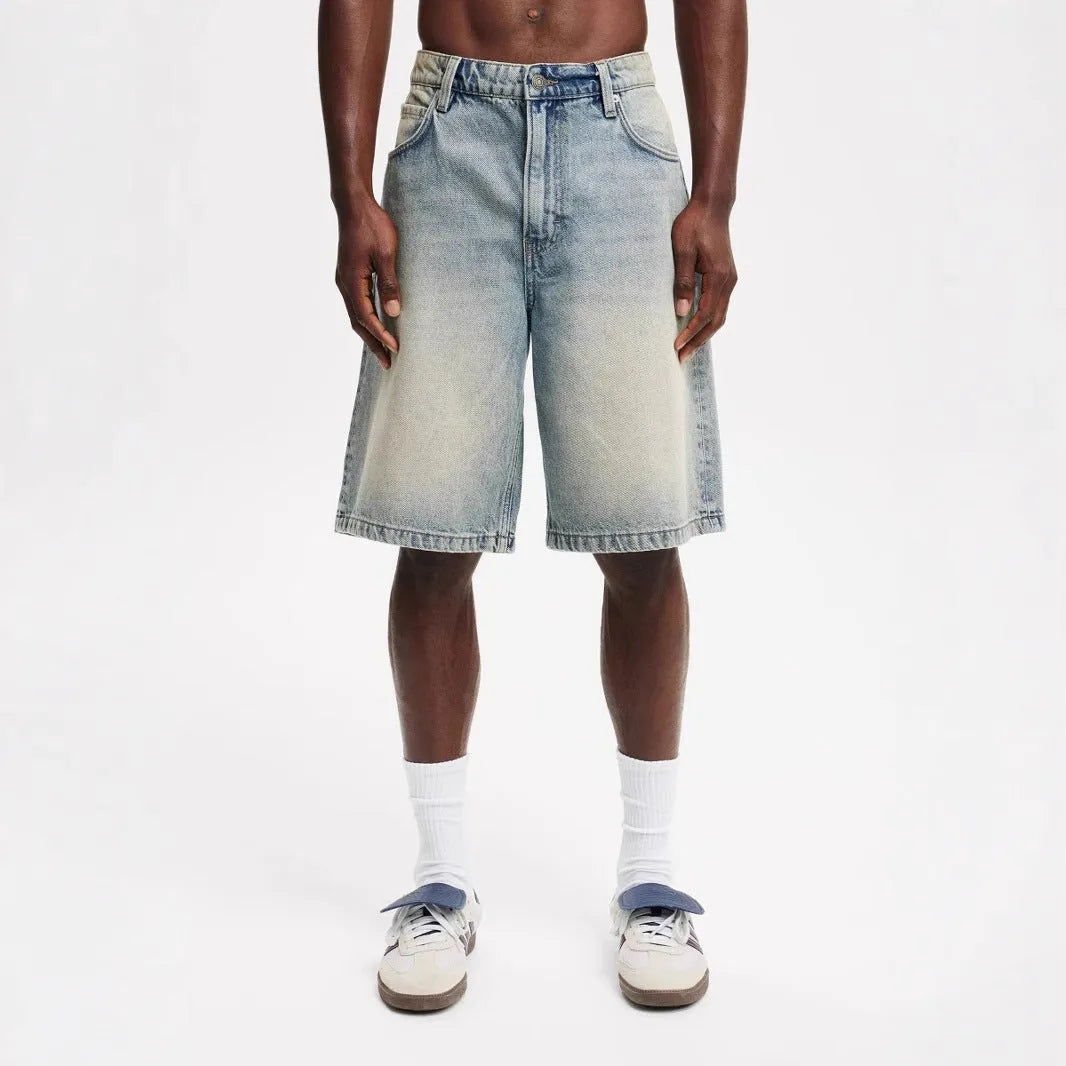 Men's loose fit light blue straight leg denim jeans on a grey background