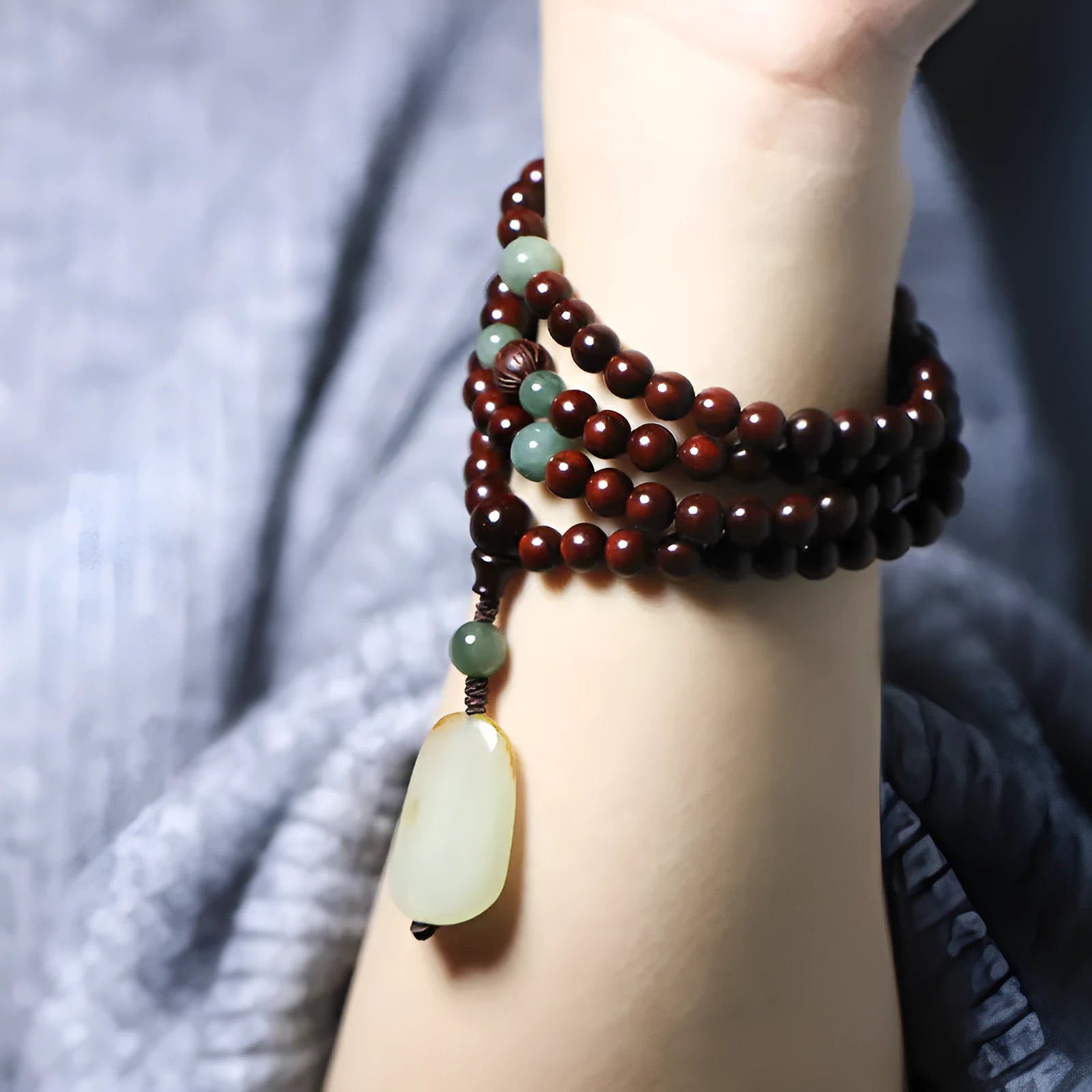 A wooden beaded bracelet with a carved green Hotian jade pendant on a natural background.