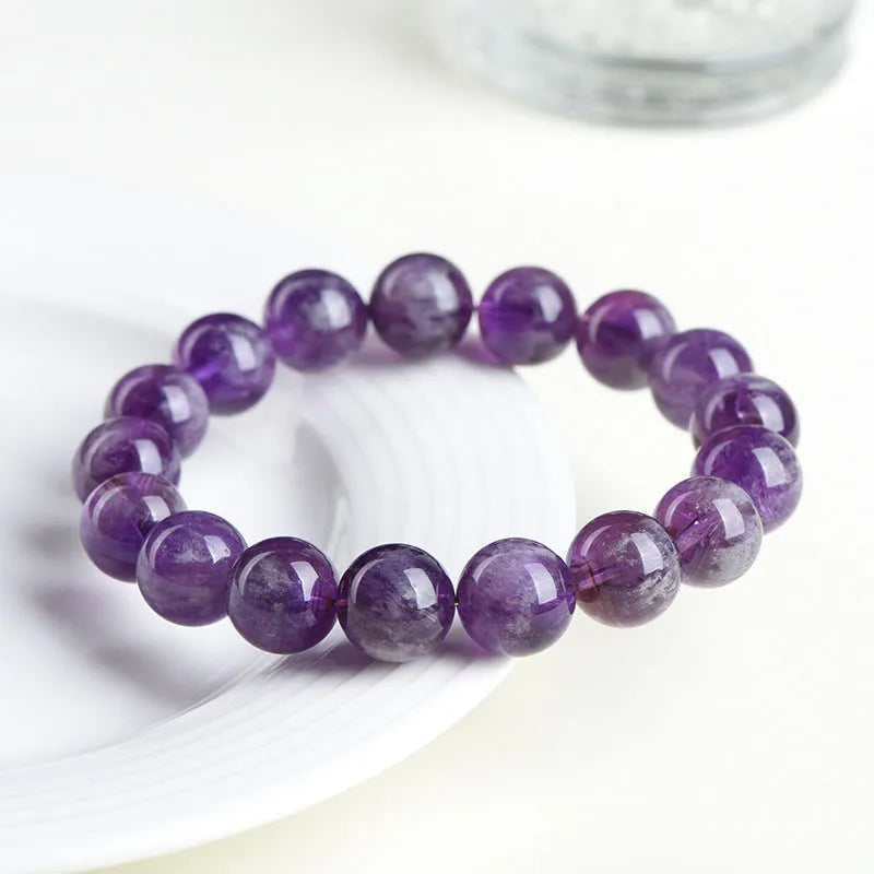 Natural feather amethyst crystal bracelet with scattered geometry beads and Ruyi element on a wrist.