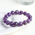 Natural feather amethyst crystal bracelet with scattered geometry beads and Ruyi element on a wrist.