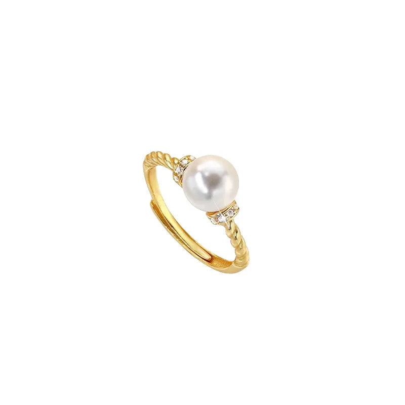 Adjustable geometric twist ring in copper with a central natural pearl on a model's finger.