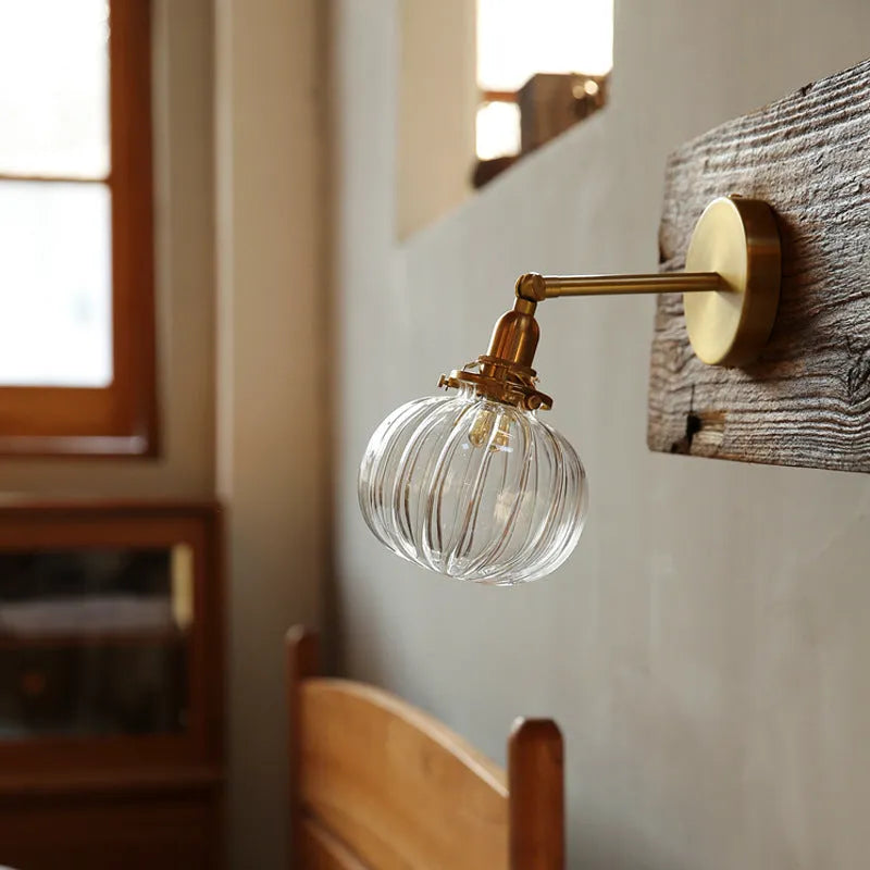 Hand-blown transparent water ripple glass wall lamp mounted on a beige wall, emitting a soft amber glow