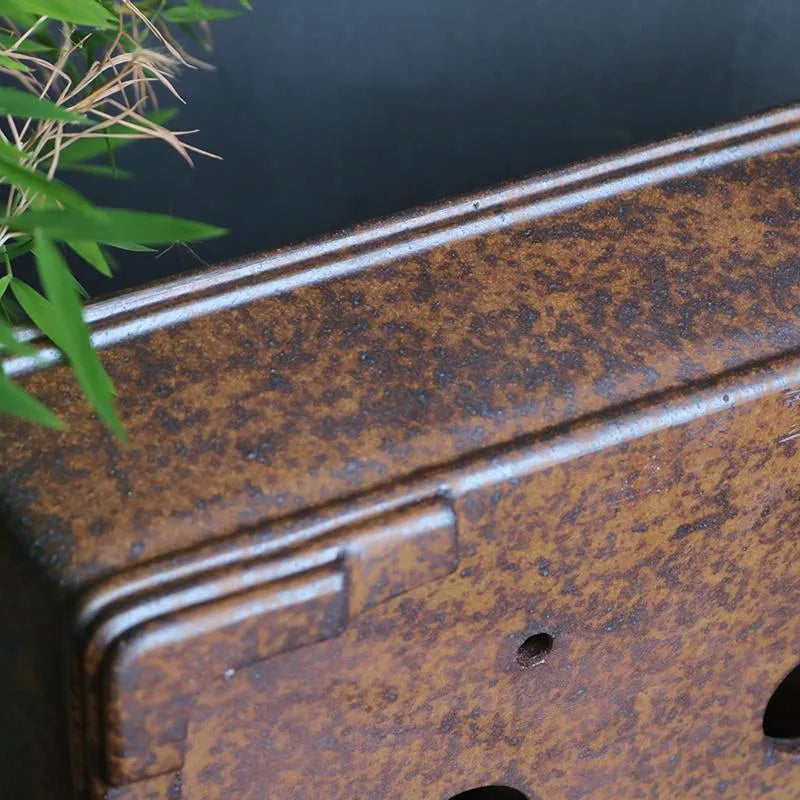 Rectangular purple sand bonsai pot with burnt pine tree decoration, shown on a garden surface.