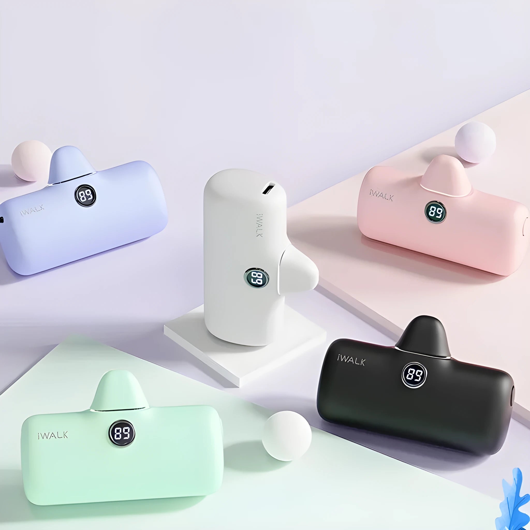 Small white cylindrical lipstick-style power bank showing digital battery percentage screen on a wooden table.