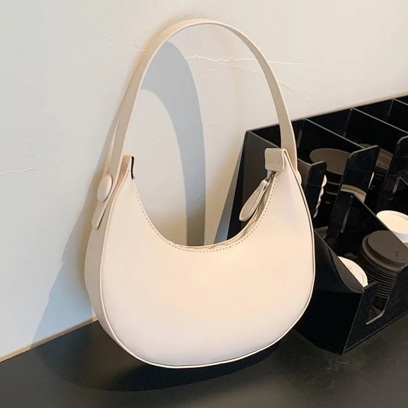 Women's retro dumpling-shaped PU shoulder bag in cream yellow with a zippered compartment.