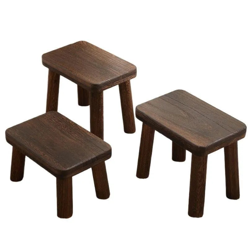 Distressed solid wood household stool for changing shoes in a living room setting.