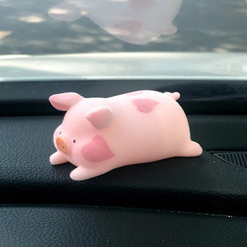 A cute cartoon pig resin figurine car decoration accessory on a dashboard.