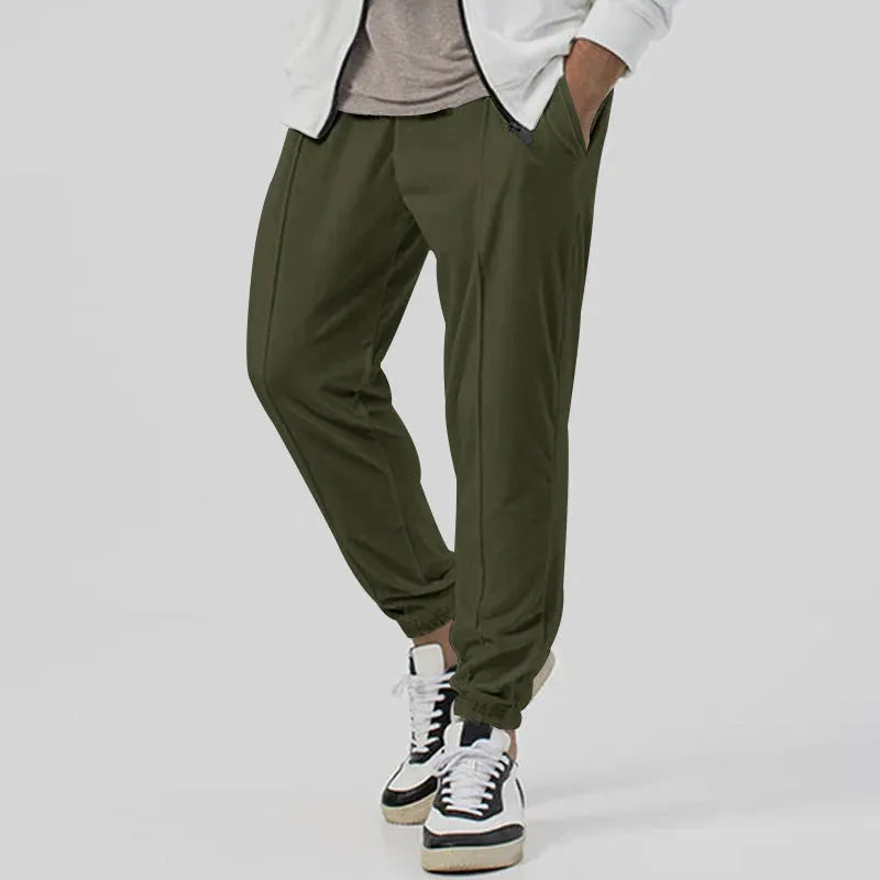Man wearing grey loose tapered casual sweatpants with a straight leg and elasticated waistband.