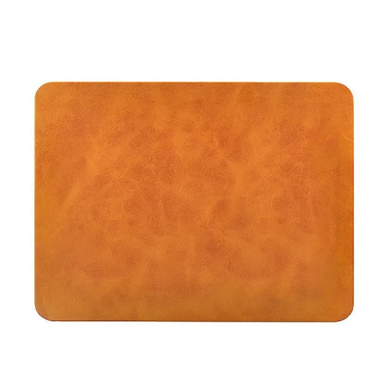 Brown leather wireless charging mouse pad on a wooden desk with a phone charging on it.