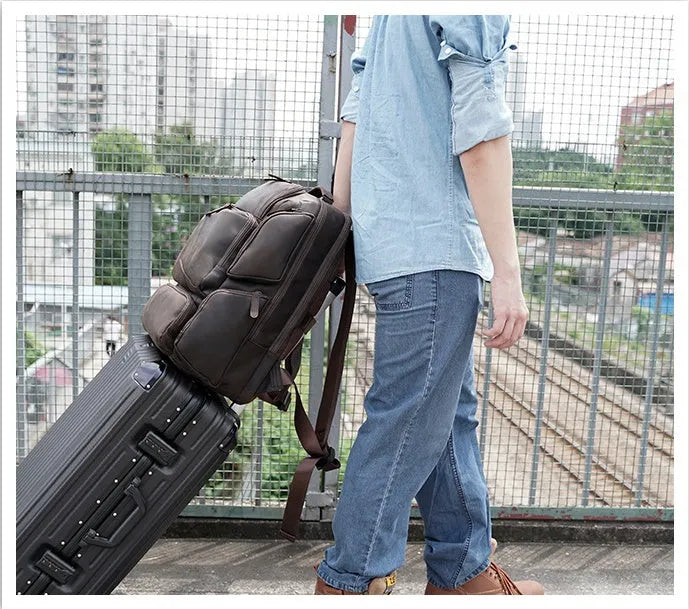 Dark brown genuine leather backpack for a 17-inch laptop, showing multiple pockets and double shoulder straps.
