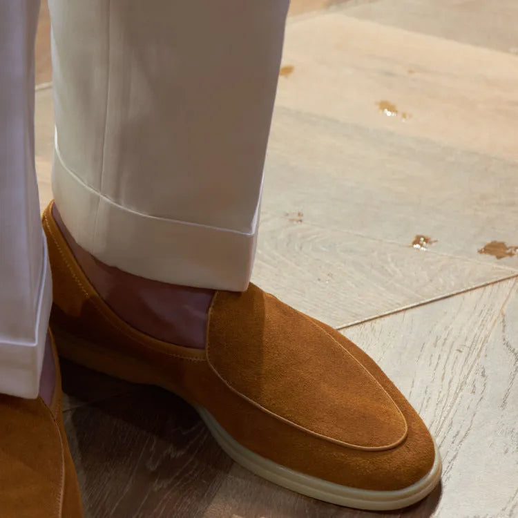 British handmade brown leather men's loafers with a flat TPR sole on a wooden surface.