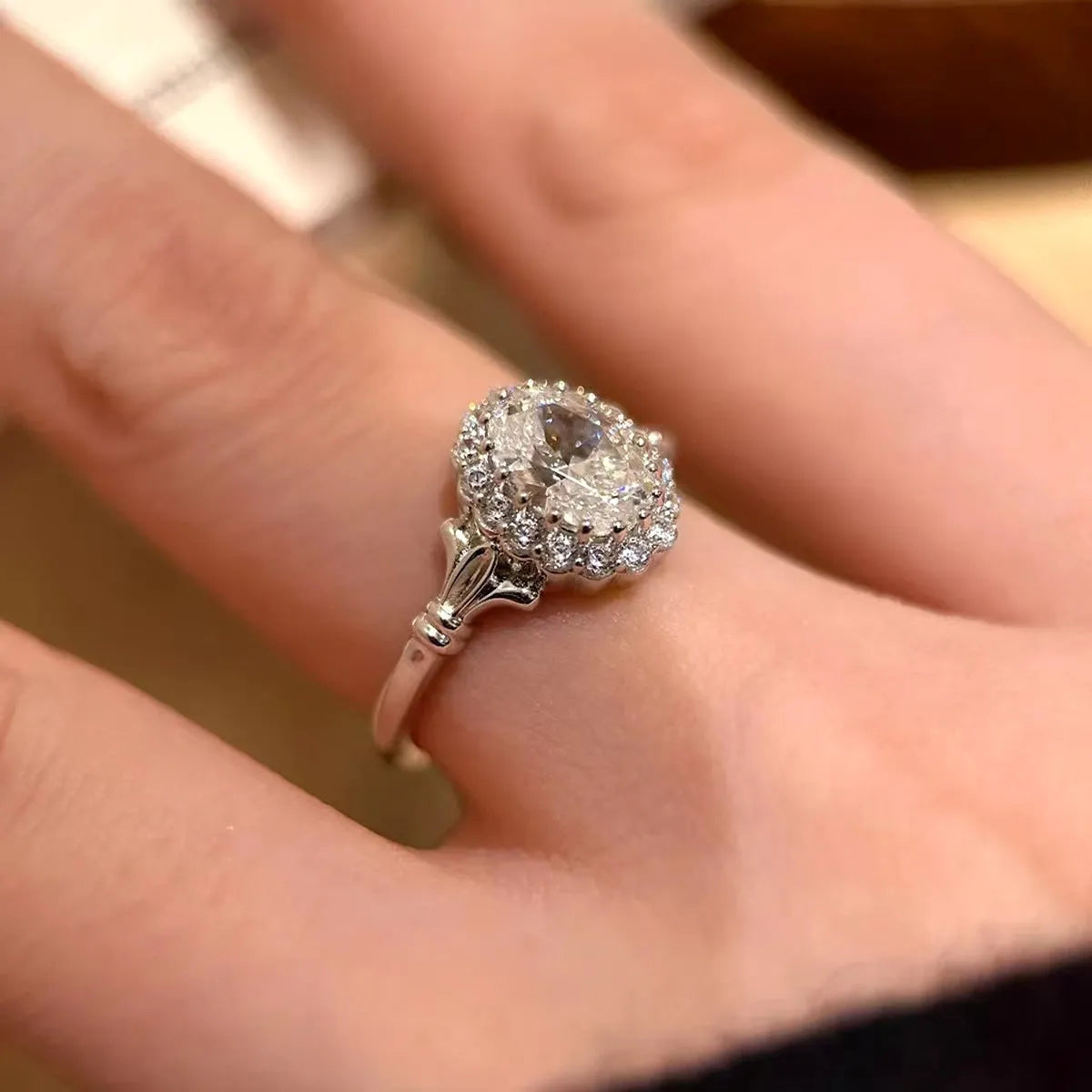 Silver geometric elliptical ring with large diamond on model's index finger, showcasing adjustable opening.