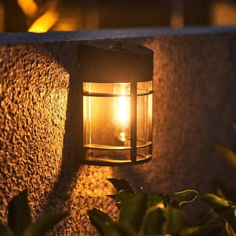 Small solar-powered outdoor wall light with warm white glow, mounted on an exterior wall.
