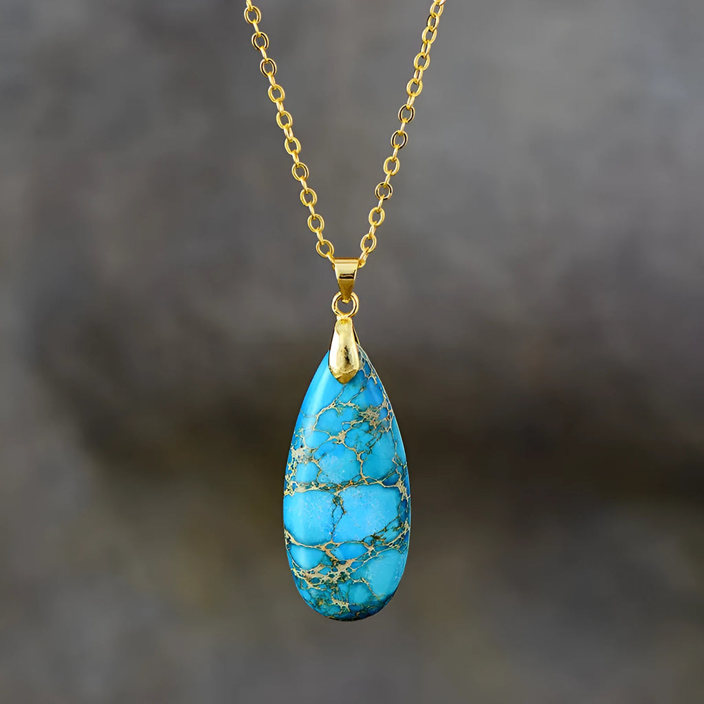 Close-up of an Emperor Stone necklace with a teardrop-shaped green jade pendant on a gold-plated chain, showing natural stone veining.
