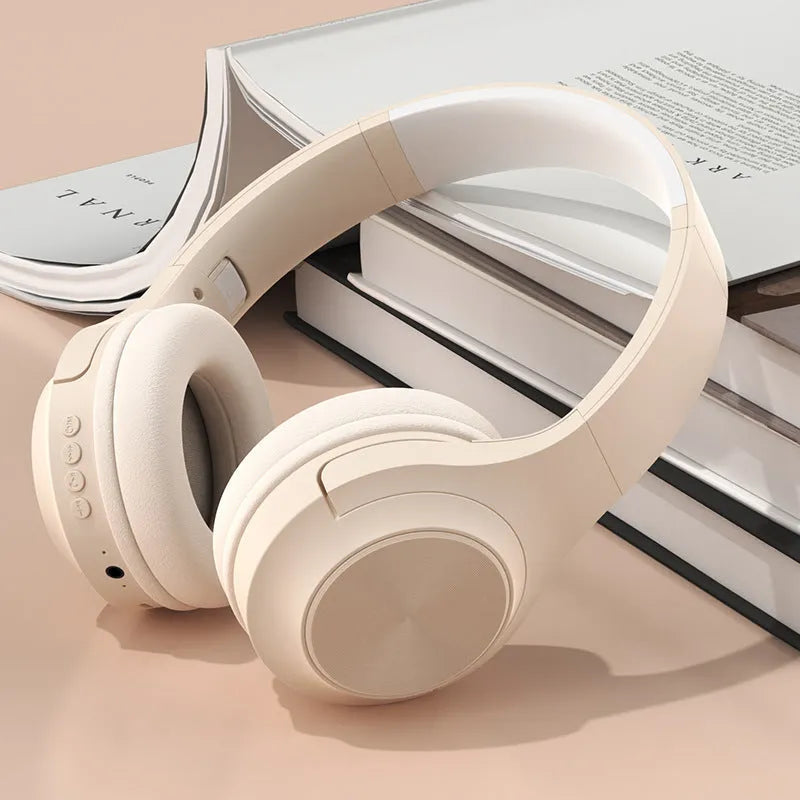 Over-ear wireless Bluetooth headset in Ivory White with a matching charging case on a table.