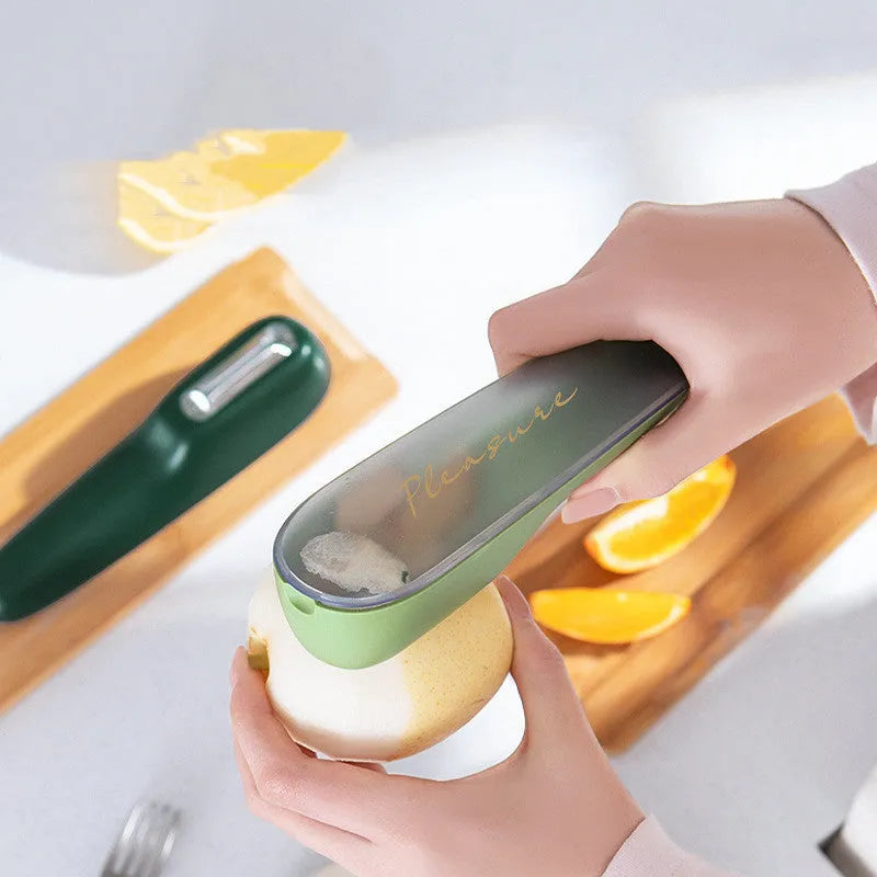 Dark green kitchen peeler with storage tube, non-slip handle, and stainless steel blade on a kitchen counter.