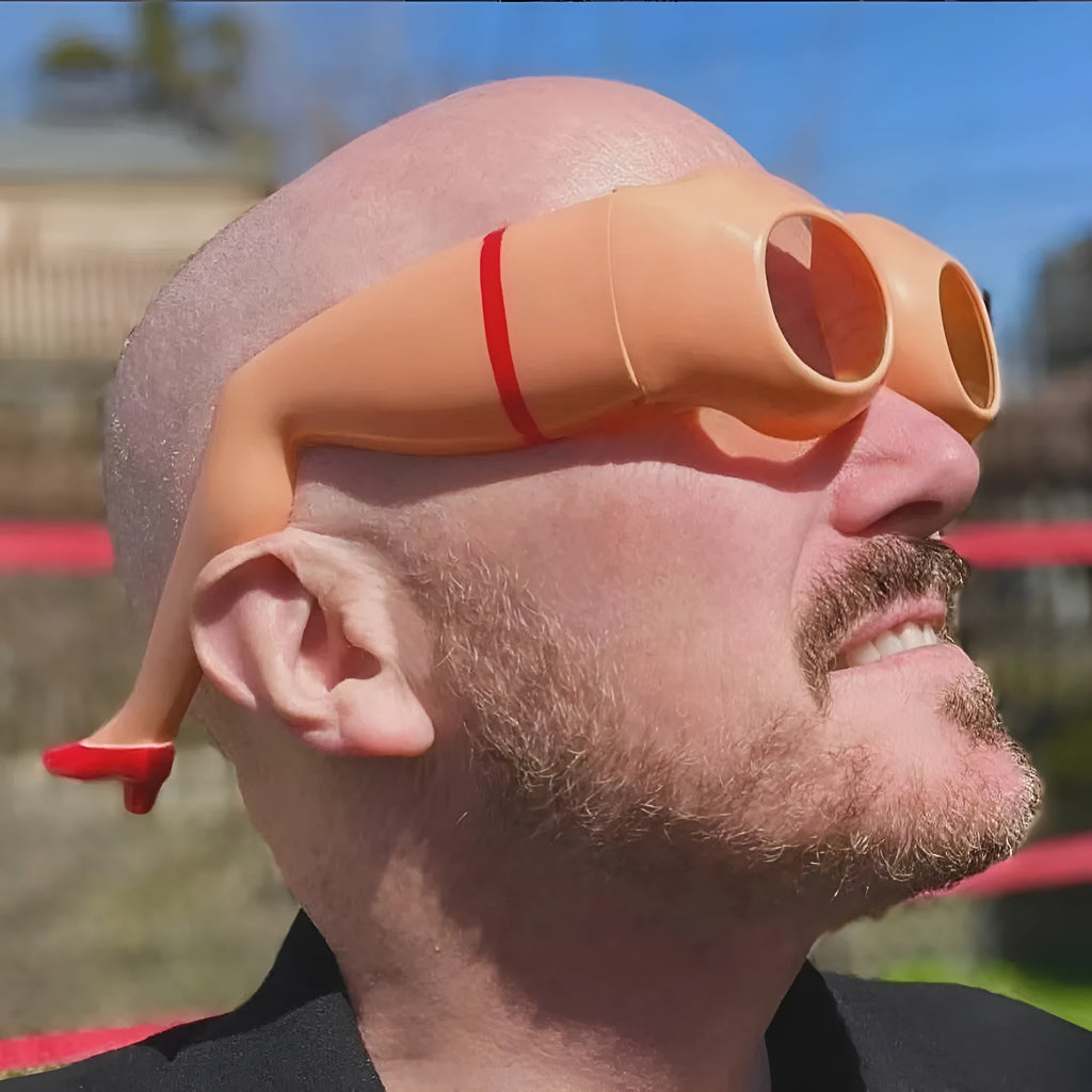 Orange novelty sunglasses with a sculptural leg and hip design on a white background.
