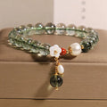 Green phantom quartz crystal bracelet for women with small shell flower and Bells of Ireland design details.