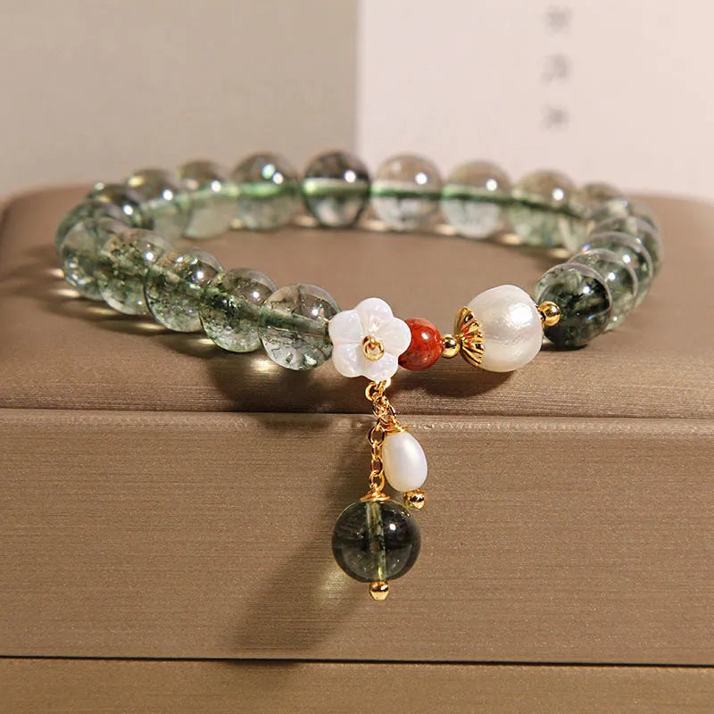 Green phantom quartz crystal bracelet for women with small shell flower and Bells of Ireland design details.