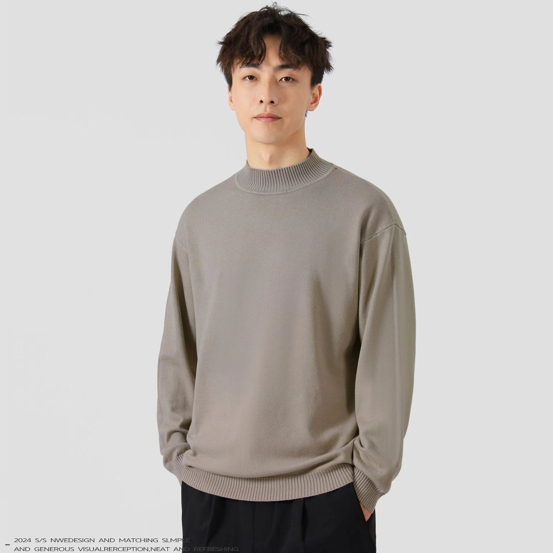 Man wearing a loose-fit long-sleeve solid colour sweater in a casual setting.