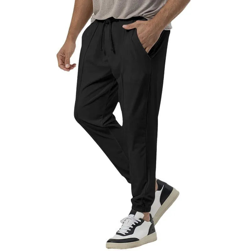 Man wearing grey loose tapered casual sweatpants with a straight leg and elasticated waistband.