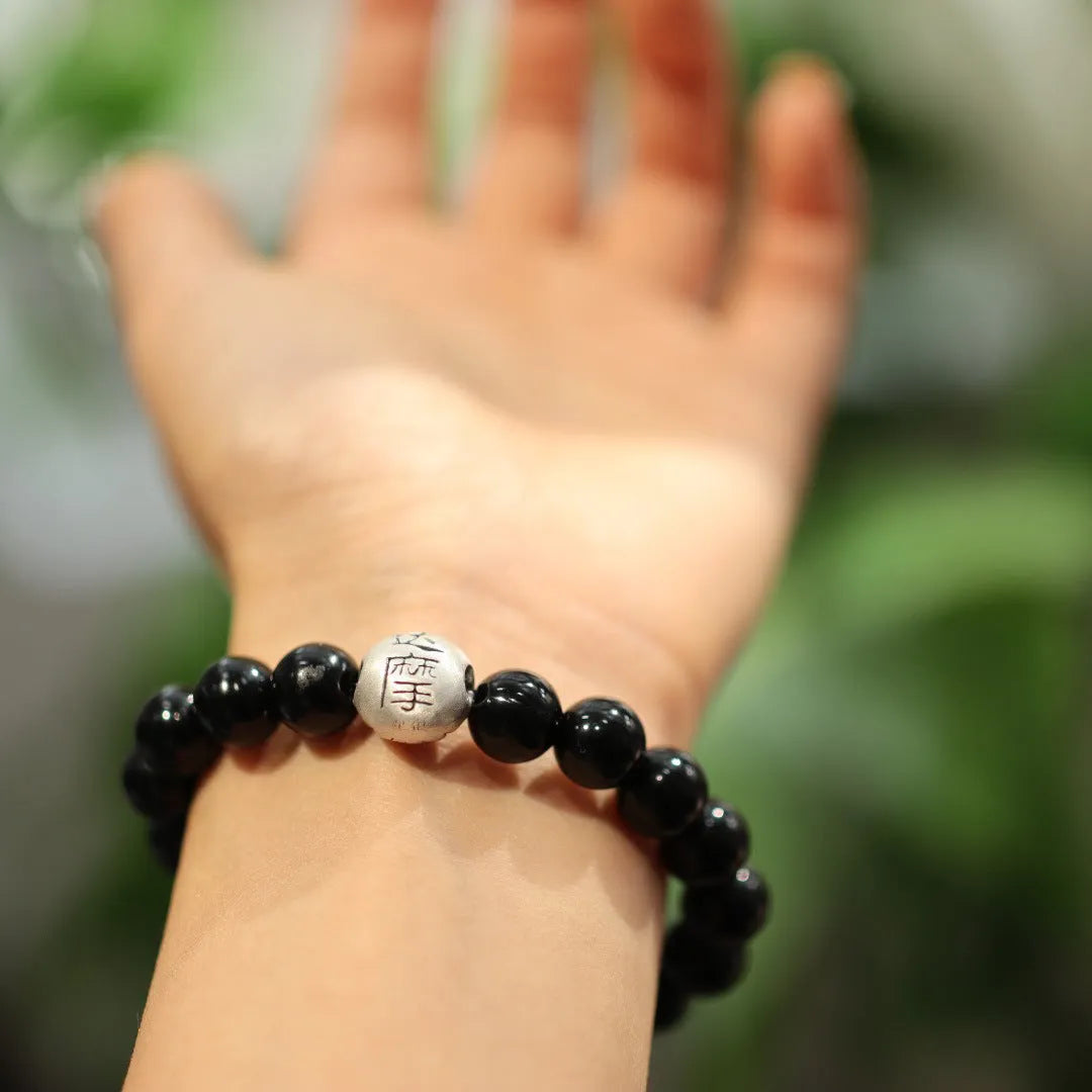 Close-up of a women's bracelet with large black agate beads and a sterling silver clasp on a wrist.