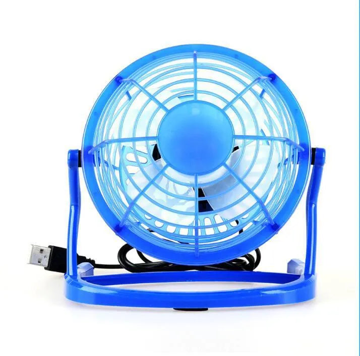 Mini adjustable tilt USB desk fan in black, shown on a desk next to a laptop
