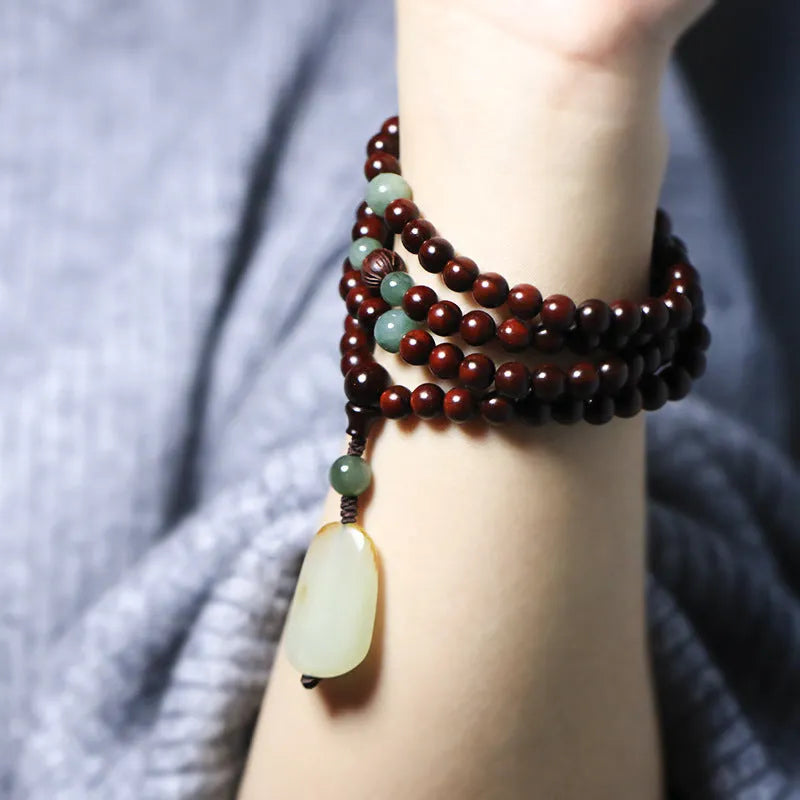 A wooden beaded bracelet with a carved green Hotian jade pendant on a natural background.