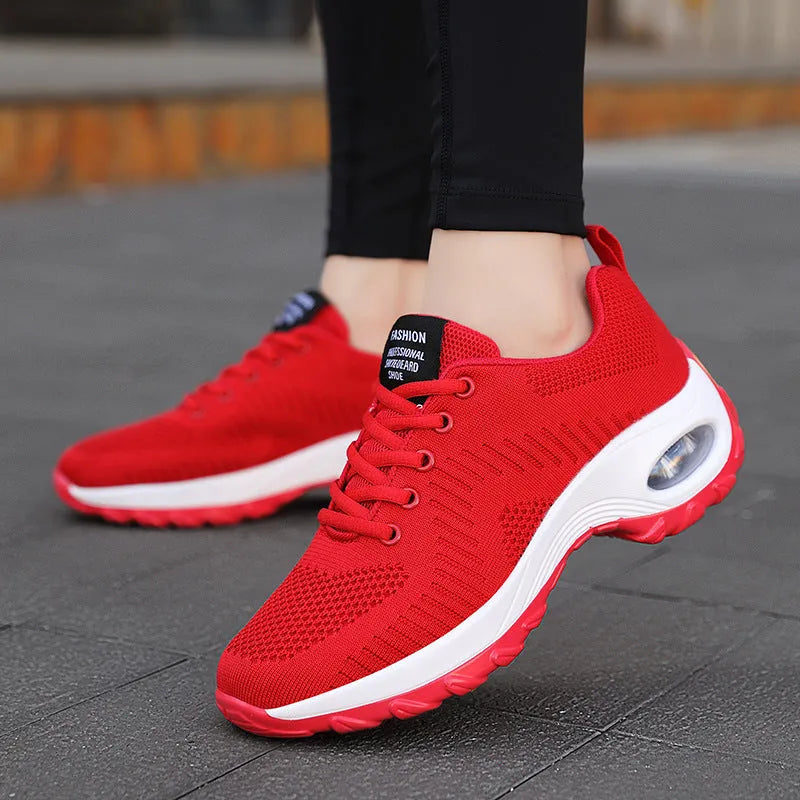 Red and black women's low-top mesh sneakers with front laces and a flat sole on a white background.
