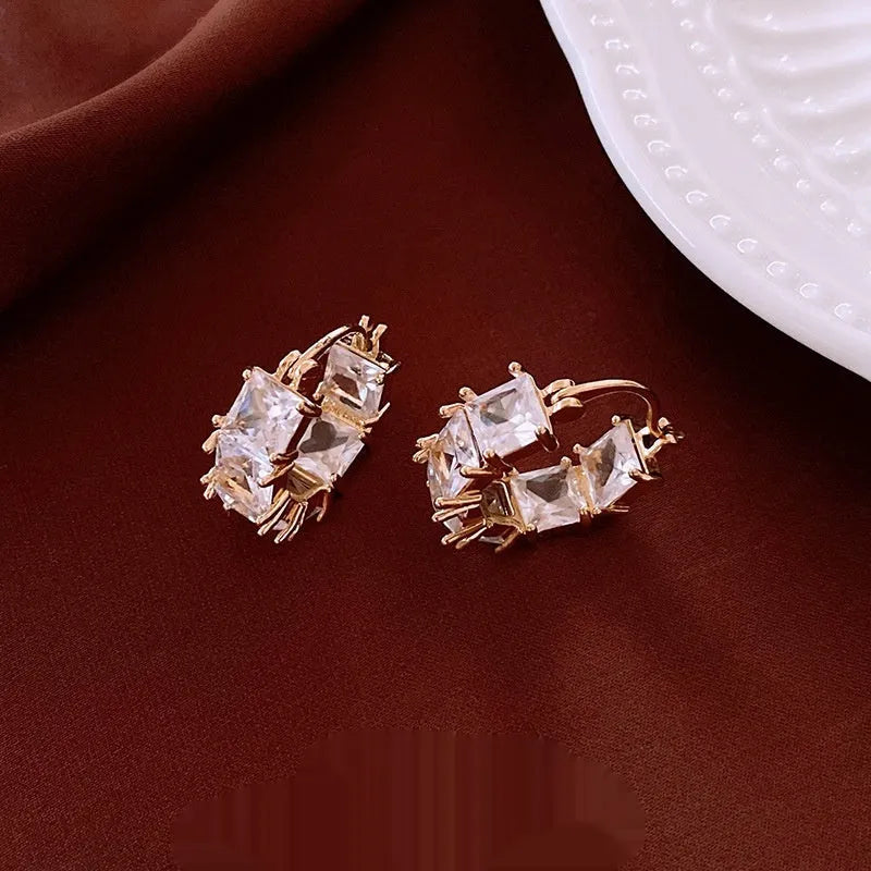 Gold-coloured U-shaped copper earrings with micro-inlaid zircon stones, geometric quadrilateral design, clip-on style.