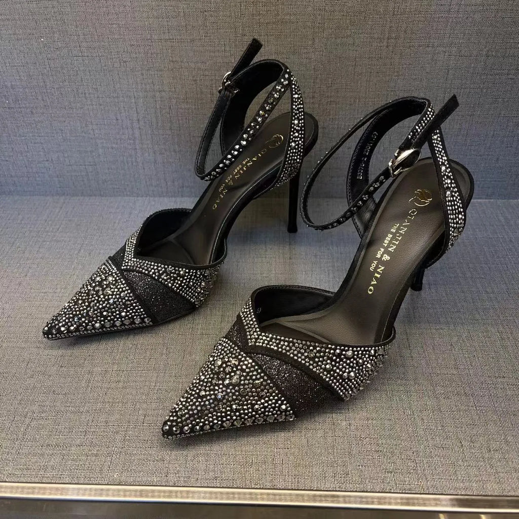 Women's black hollow high heel shoe with red sole, stiletto heel, and pointed toe on a plain background.