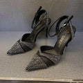 Women's black hollow high heel shoe with red sole, stiletto heel, and pointed toe on a plain background.