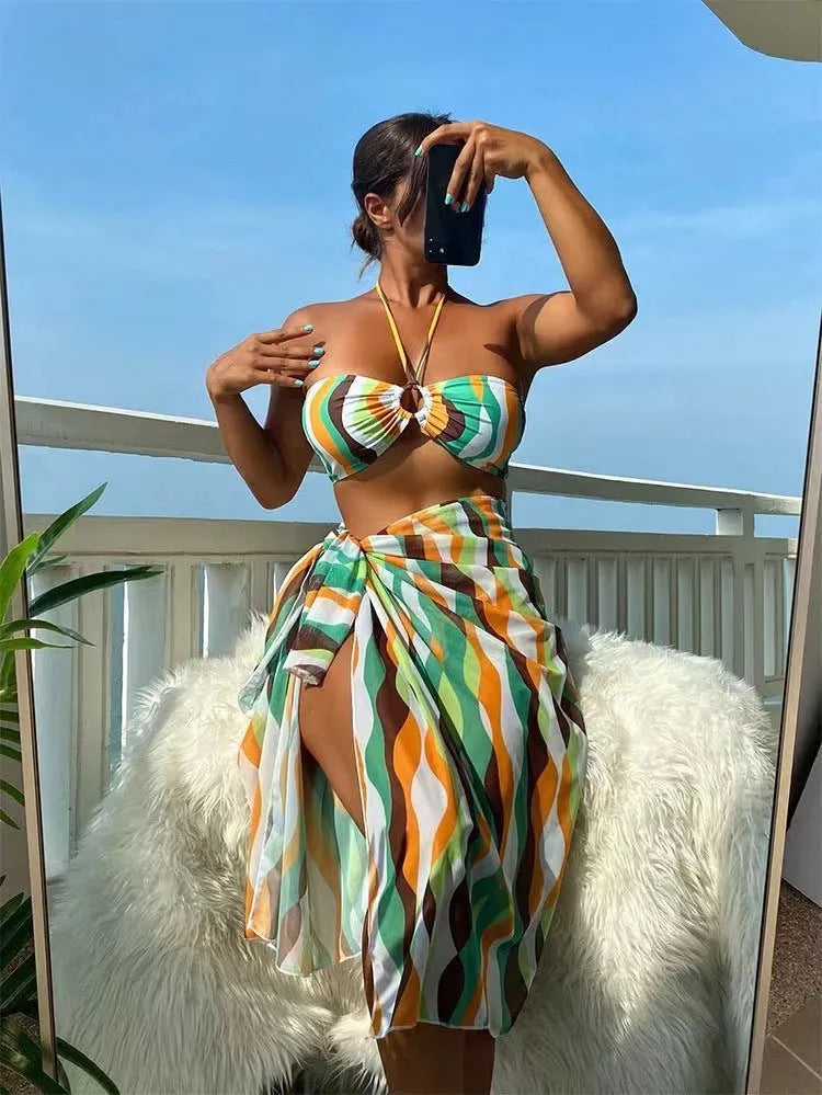 Yellow green printed women's bikini set with top, briefs, and matching beach skirt laid flat.