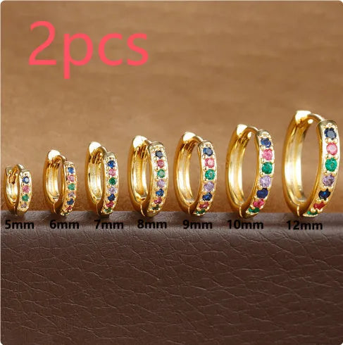 Gold, rose gold, and silver circle-shaped perforated stud earrings on a plain background.