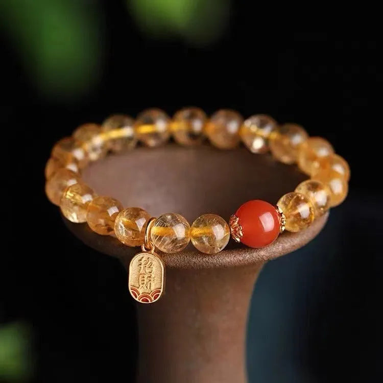 Natural red agate bead bracelet with gold-coloured spacers on a wrist.