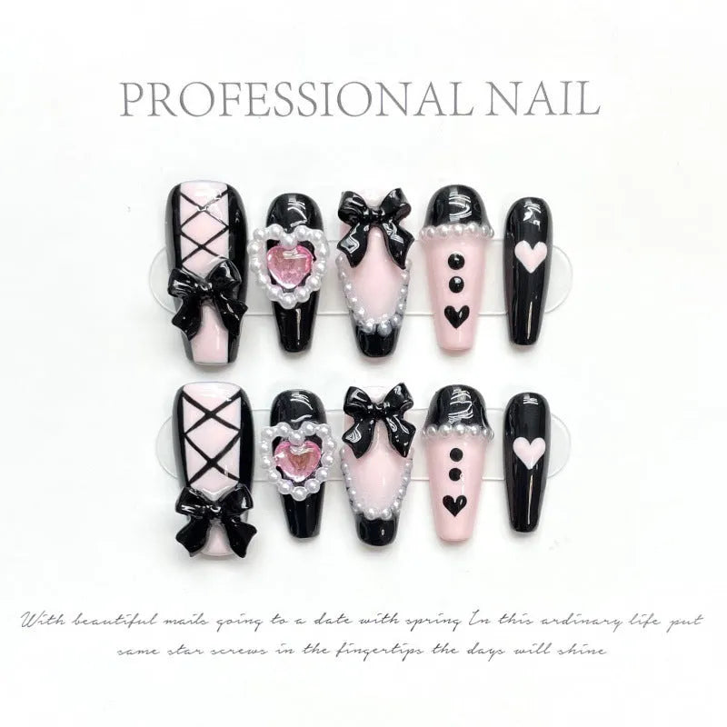 Black pink heart-shaped false nails with hand-painted bow design, Cat's Eye style, in mid-length profile.