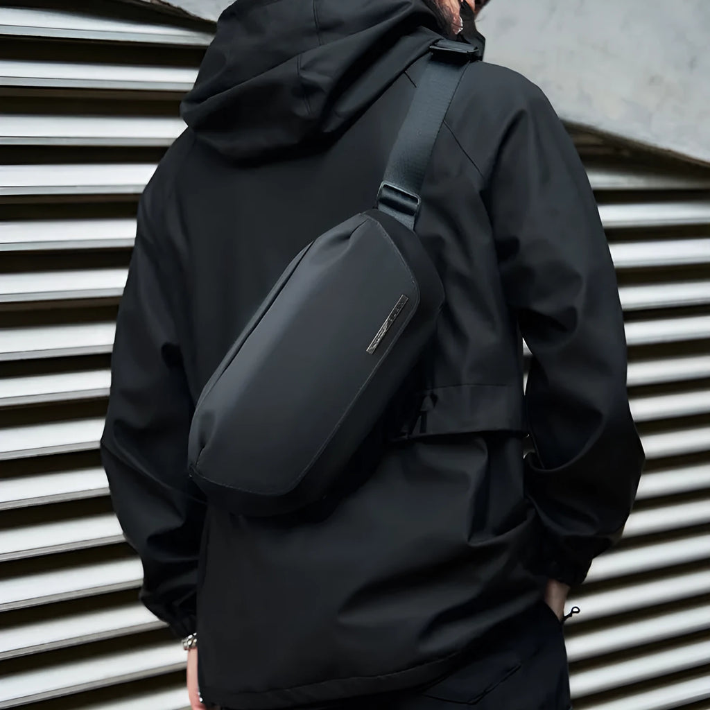 Black men's oxford cloth messenger bag with crossbody strap and sewing thread detailing.