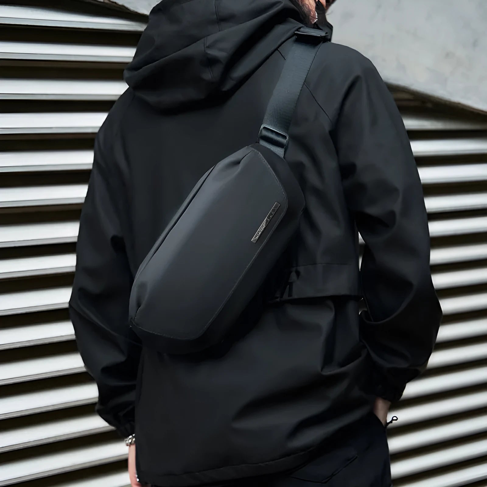Black men's oxford cloth messenger bag with crossbody strap and sewing thread detailing.