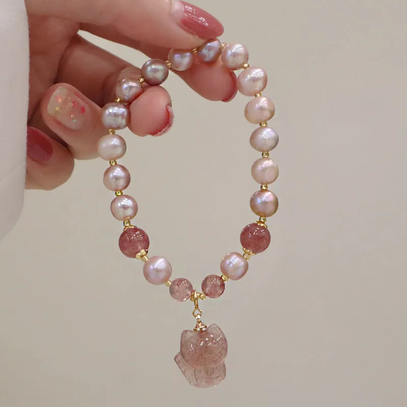Women's light pink freshwater pearl bracelet with strawberry quartz and fox charm on wrist