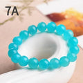 A selection of loose, polished ice-blue Amazonite beads in various sizes next to a finished crystal bracelet.