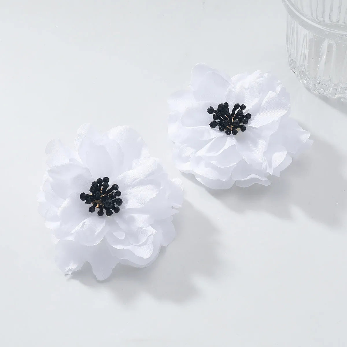 Hand-woven white plastic resin flower earrings for women fashion OL style on display