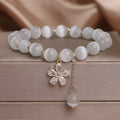 White cats eye crystal bracelet with flower charms, tassels and safety buckle closure