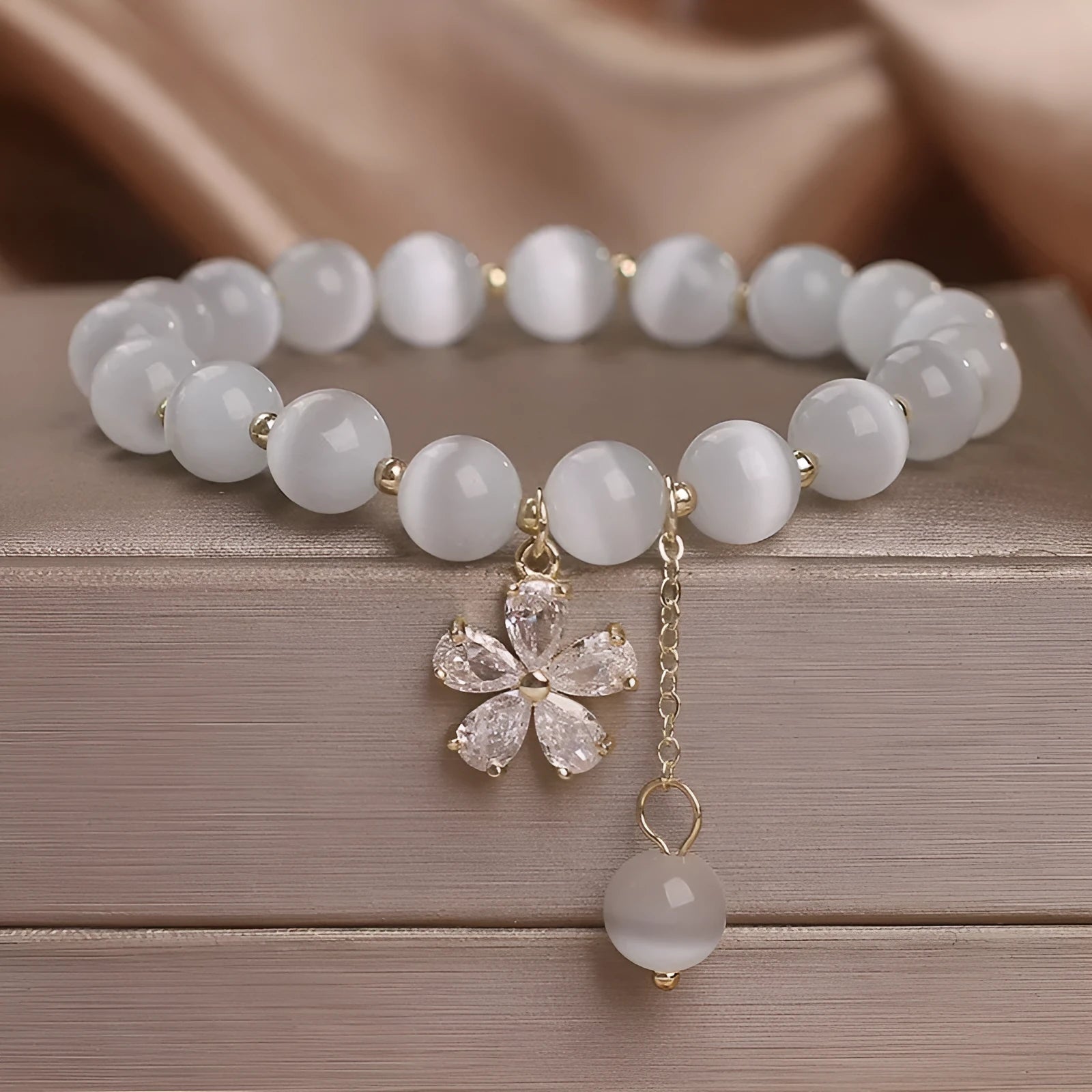 White cats eye crystal bracelet with flower charms, tassels and safety buckle closure